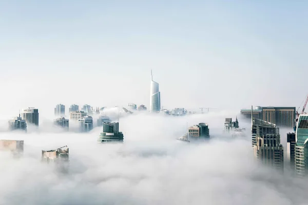 Wolkenkrabbers die boven een dikke laag mist uitsteken
