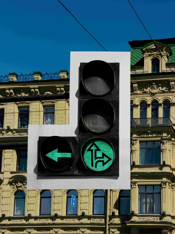 Een verkeerslicht met groene pijlen naar links, rechtdoor en rechts