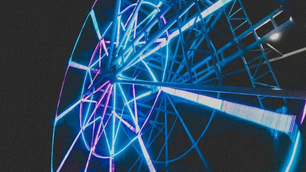 Een reuzenrad met blauw en roze neonlicht in het donker