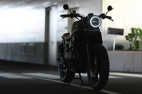 Een zwarte motor met een ronde koplamp in een parkeergarage