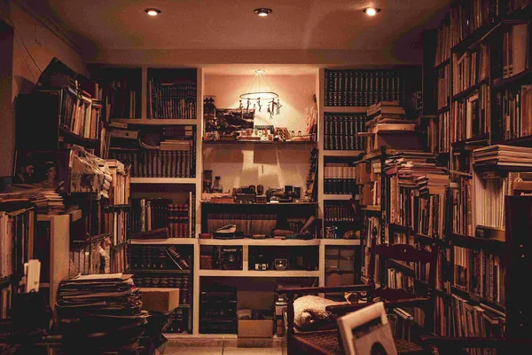 Een warm verlichte kamer met boekenkasten vol boeken