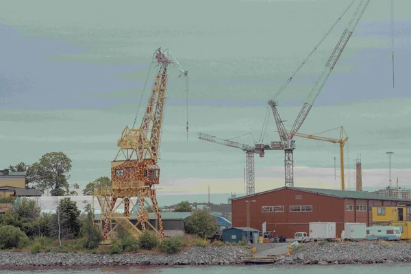 Hijskranen en een rood gebouw aan het water