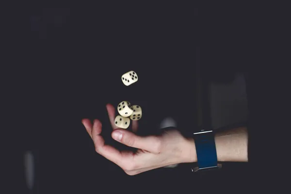 Een hand die drie dobbelstenen opgooit