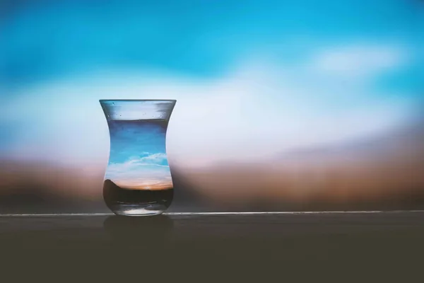 Een glas water tegen een wazige blauwe lucht